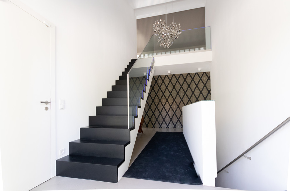 Design ideas for a contemporary wood straight staircase in Stuttgart with wood risers and glass railing.