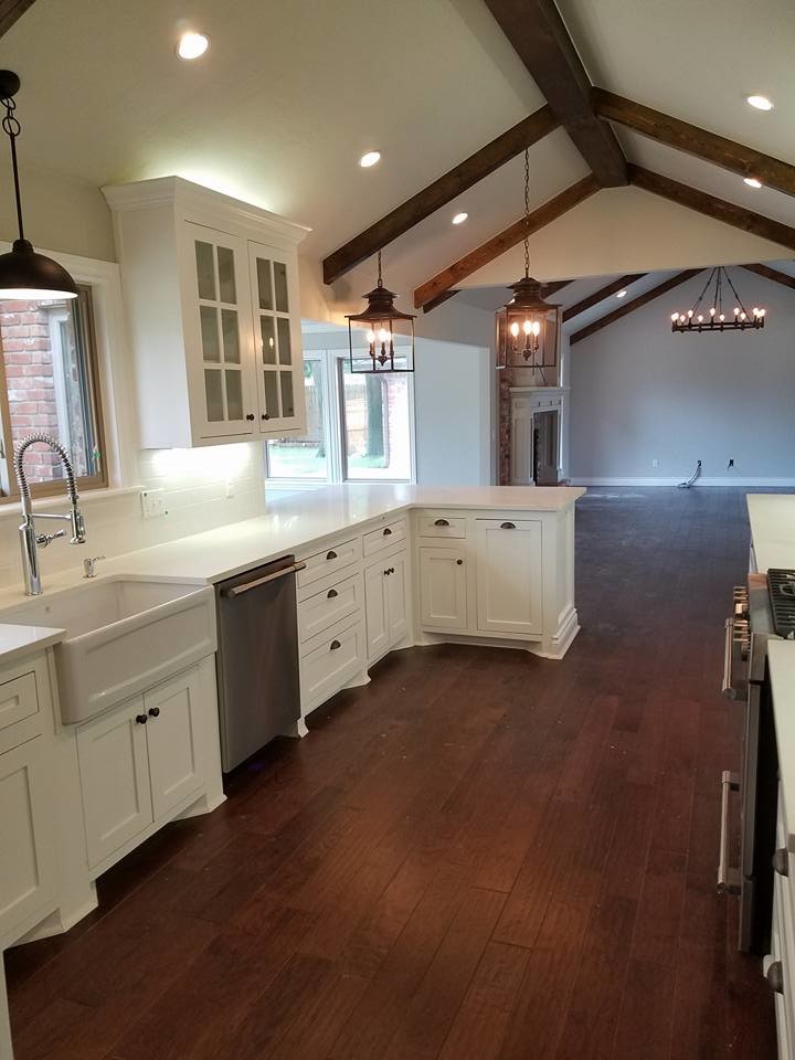Inspiration for a mid-sized country l-shaped open plan kitchen in Oklahoma City with a farmhouse sink, glass-front cabinets, white cabinets, quartzite benchtops, white splashback, subway tile splashback, stainless steel appliances, dark hardwood floors and a peninsula.