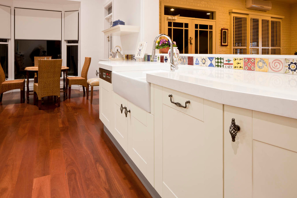 Photo of a large country kitchen in Other with a farmhouse sink, white cabinets, quartz benchtops, multi-coloured splashback, porcelain splashback, coloured appliances and dark hardwood floors.