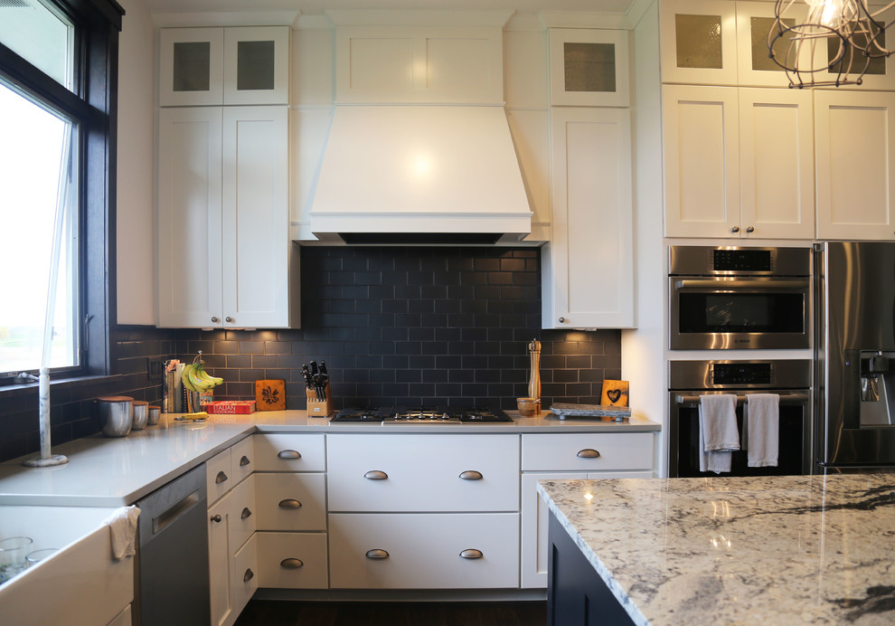 Mid-sized transitional l-shaped dark wood floor eat-in kitchen photo with a farmhouse sink, recessed-panel cabinets, white cabinets, granite countertops, black backsplash, porcelain backsplash, stainless steel appliances and an island