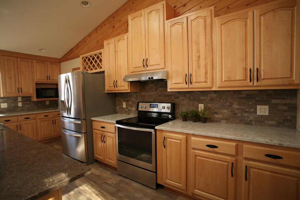 Example of a mid-sized mountain style l-shaped medium tone wood floor and brown floor open concept kitchen design with a double-bowl sink, raised-panel cabinets, light wood cabinets, quartz countertops, gray backsplash, stone tile backsplash, stainless steel appliances and an island