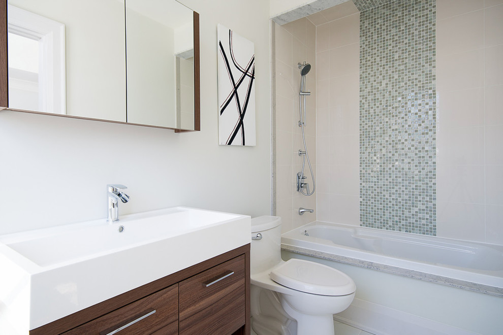 Mid-sized modern master bathroom in Toronto with flat-panel cabinets, white cabinets, a freestanding tub, an open shower, a one-piece toilet, beige tile, stone tile, white walls, ceramic floors, a trough sink and tile benchtops.