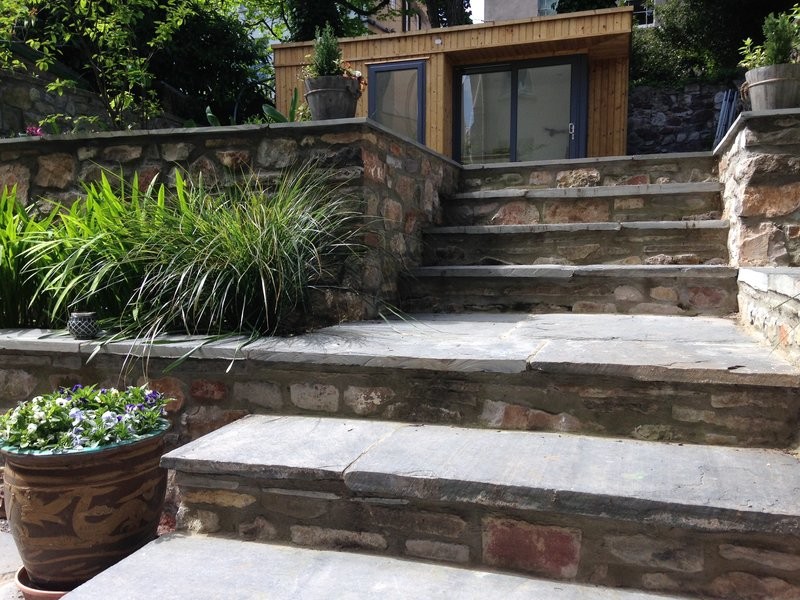Inspiration for a mid-sized contemporary backyard formal garden in Other with a retaining wall and natural stone pavers.