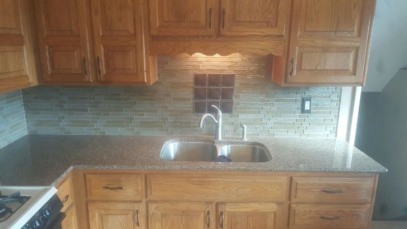 Inspiration for a transitional kitchen remodel in Chicago with raised-panel cabinets, medium tone wood cabinets, quartz countertops, green backsplash and glass tile backsplash