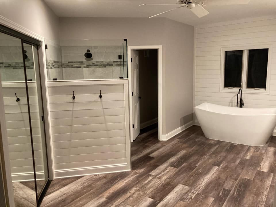 Photo of a large modern master bathroom in Kansas City with a built-in vanity, raised-panel cabinets, white cabinets, a freestanding tub, a curbless shower, grey walls, vinyl floors, an undermount sink, engineered quartz benchtops, multi-coloured floor, a hinged shower door, white benchtops, an enclosed toilet, a double vanity and planked wall panelling.