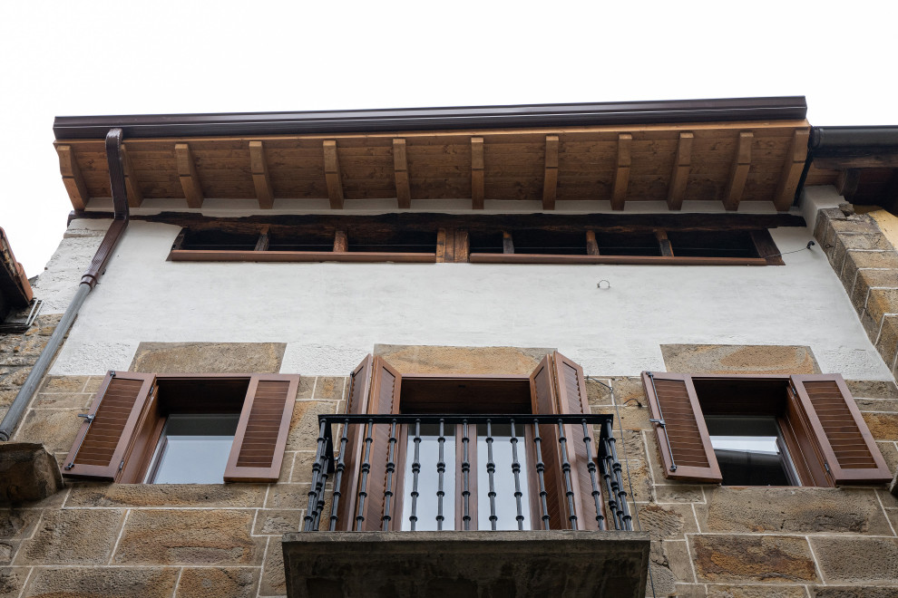 Источник вдохновения для домашнего уюта: трехэтажный многоквартирный дом в стиле рустика с облицовкой из камня, двускатной крышей, крышей из смешанных материалов и коричневой крышей