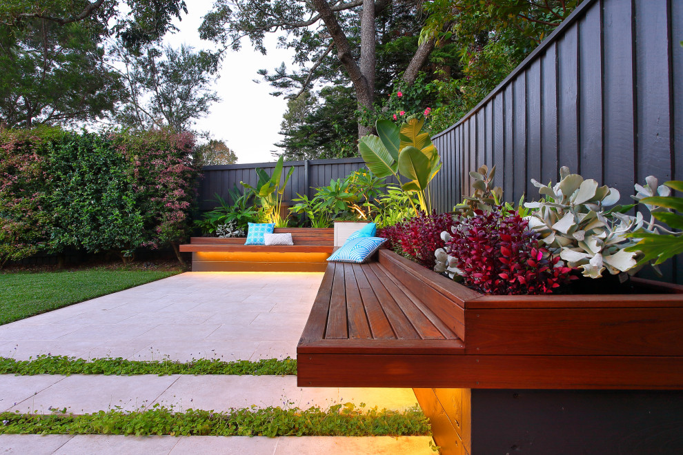 Photo of a small contemporary courtyard partial sun garden in Sydney with with raised garden bed, natural stone pavers and a wood fence.