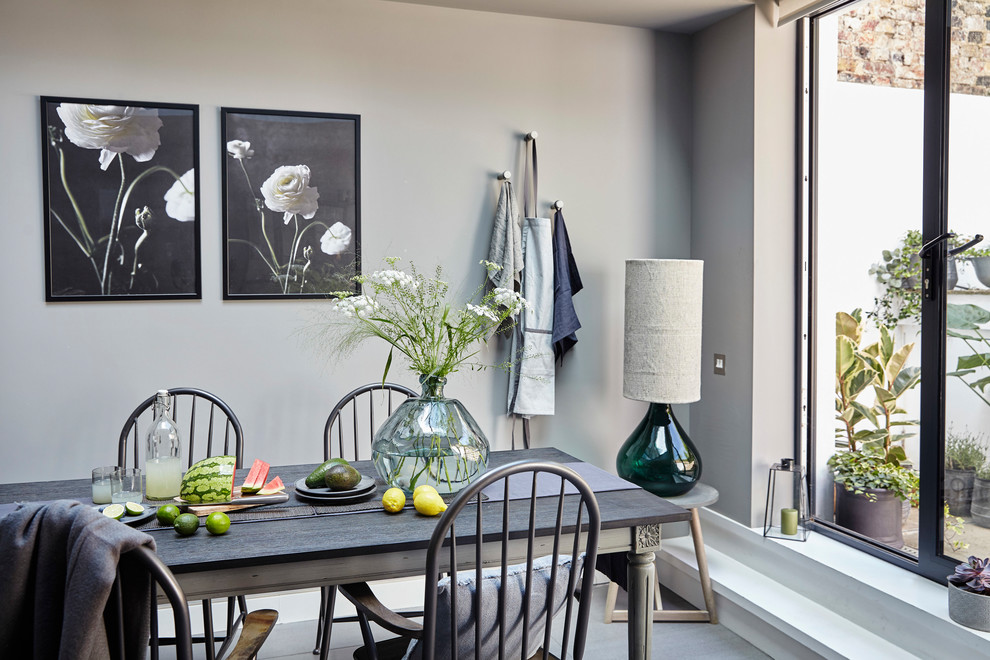 This is an example of a transitional dining room in London with grey walls and grey floor.