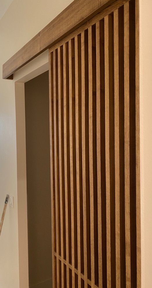 Mid-sized contemporary gender-neutral walk-in wardrobe in Paris with louvered cabinets and light wood cabinets.