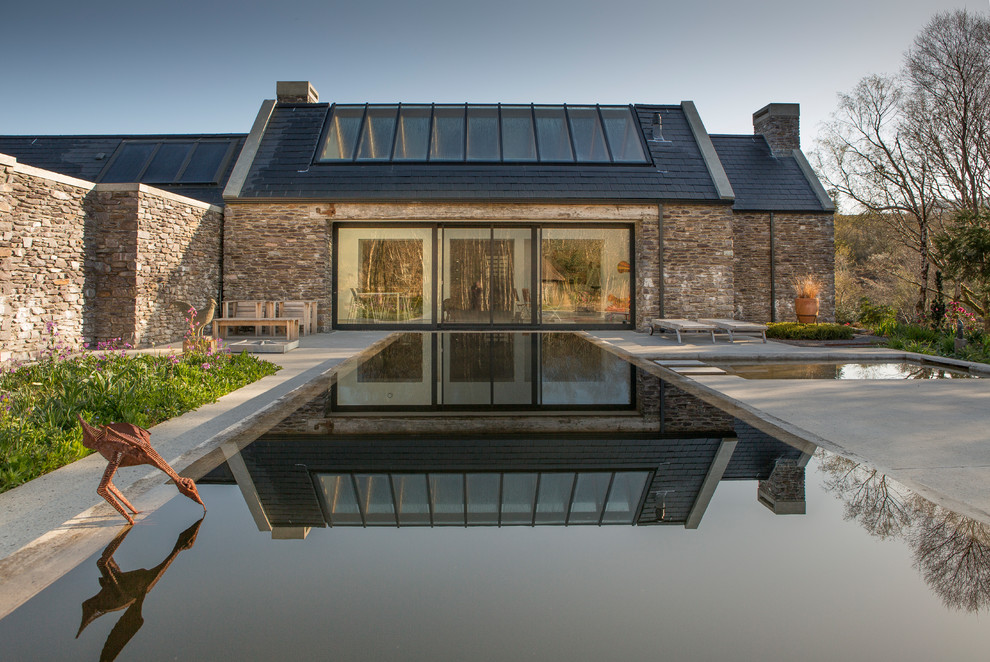 This is an example of a contemporary backyard rectangular infinity pool in Other with a pool house.