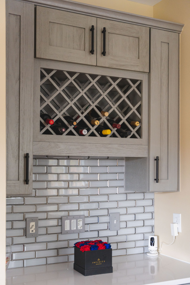 Example of a large transitional u-shaped medium tone wood floor and brown floor eat-in kitchen design with a farmhouse sink, shaker cabinets, gray cabinets, quartz countertops, gray backsplash, glass tile backsplash, stainless steel appliances, an island and white countertops