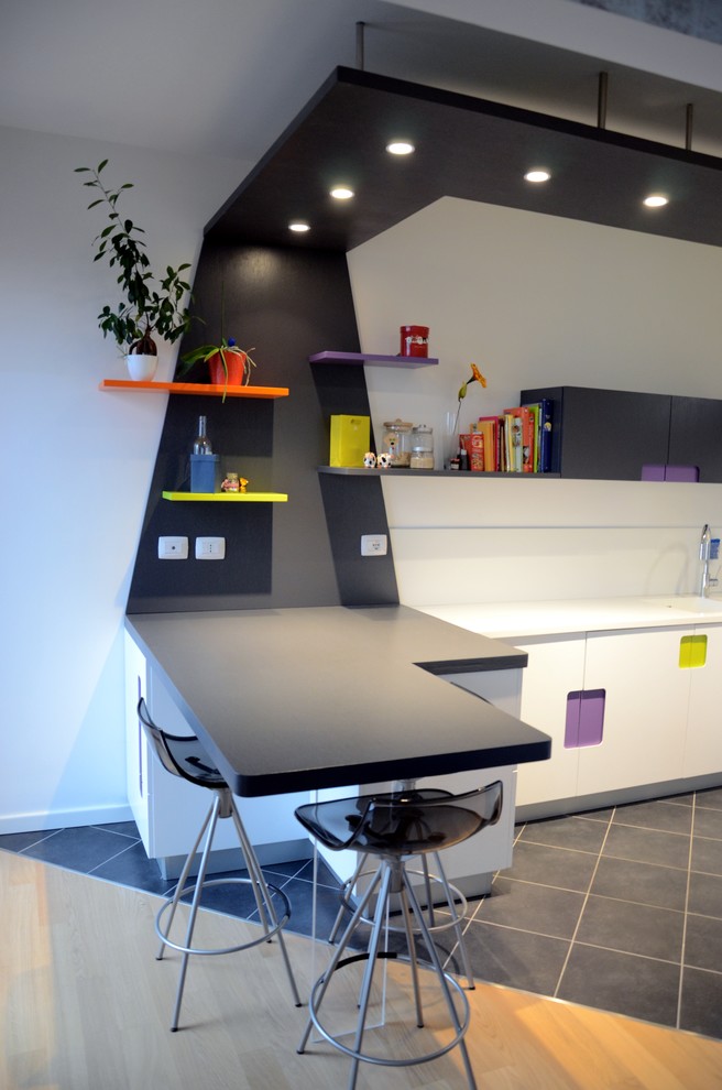 This is an example of a small modern u-shaped separate kitchen in Milan with an integrated sink, flat-panel cabinets, dark wood cabinets, quartz benchtops, white splashback, stone slab splashback, panelled appliances, porcelain floors and a peninsula.
