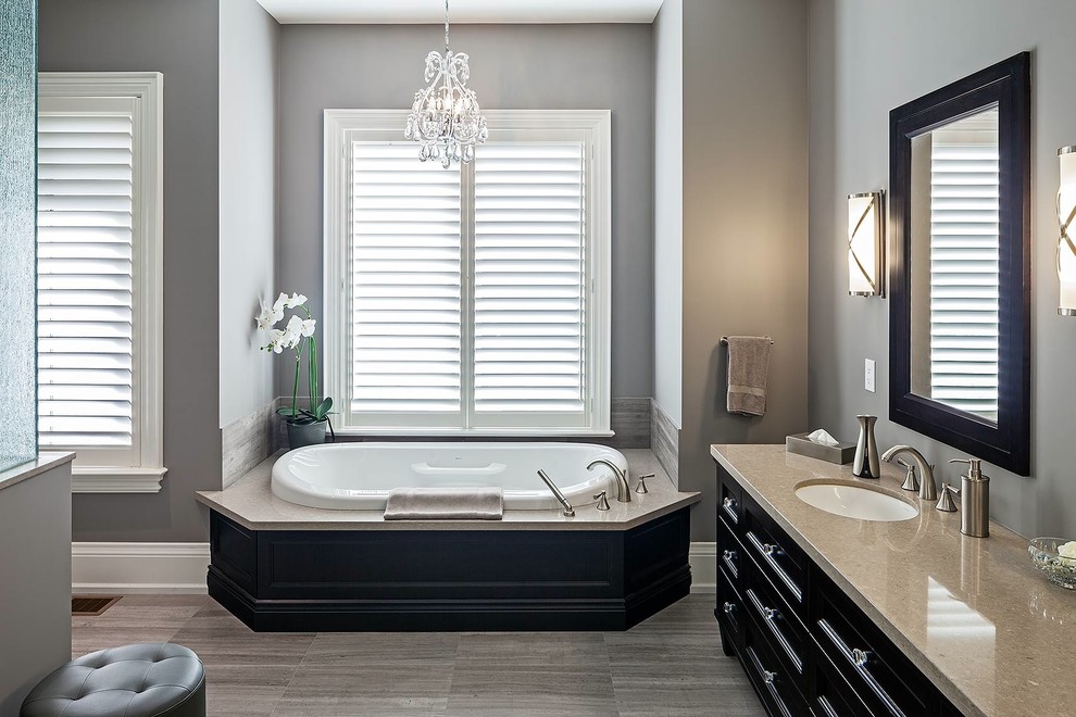 Large transitional master bathroom in Toronto with a drop-in sink, recessed-panel cabinets, black cabinets, granite benchtops, a drop-in tub, brown tile and grey walls.