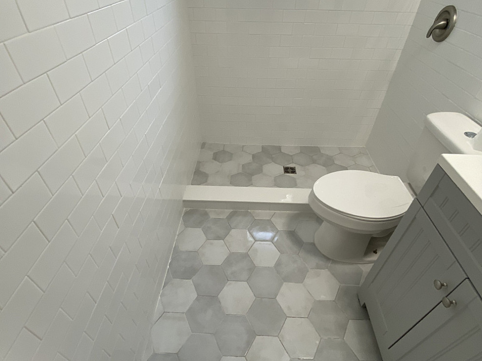 Cette image montre une petite salle d'eau design avec des portes de placard grises, une douche ouverte, un carrelage blanc, un carrelage métro, un mur blanc, un sol en marbre, un sol gris, une cabine de douche à porte battante, meuble simple vasque et meuble-lavabo sur pied.