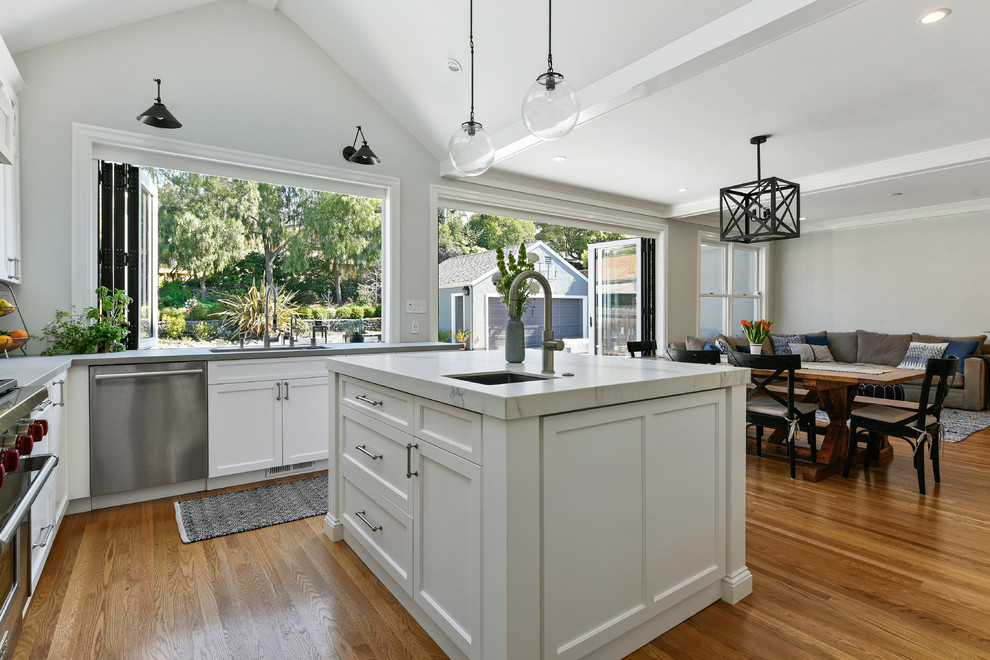 Inspiration for a mid-sized transitional u-shaped open plan kitchen in San Francisco with an undermount sink, shaker cabinets, white cabinets, concrete benchtops, white splashback, marble splashback, stainless steel appliances, medium hardwood floors, with island, brown floor and grey benchtop.
