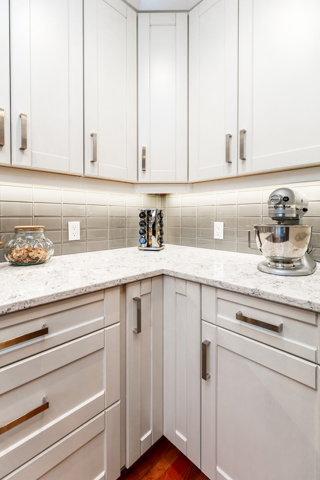 Example of a large transitional u-shaped medium tone wood floor eat-in kitchen design in Calgary with an undermount sink, shaker cabinets, white cabinets, gray backsplash, glass tile backsplash, stainless steel appliances, an island and marble countertops