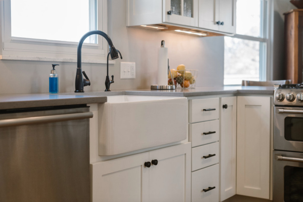 Inspiration for a mid-sized transitional l-shaped medium tone wood floor and brown floor eat-in kitchen remodel in Columbus with a farmhouse sink, shaker cabinets, white cabinets, solid surface countertops, gray backsplash, matchstick tile backsplash, stainless steel appliances and no island