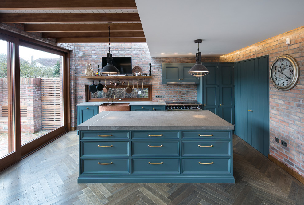 Mid-sized industrial eat-in kitchen in Dublin with a farmhouse sink, shaker cabinets, blue cabinets, quartz benchtops, black appliances, dark hardwood floors, with island and grey benchtop.