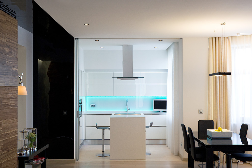 Inspiration for a large contemporary l-shaped separate kitchen in Moscow with an integrated sink, flat-panel cabinets, white cabinets, solid surface benchtops, white splashback, glass sheet splashback, stainless steel appliances, porcelain floors and with island.