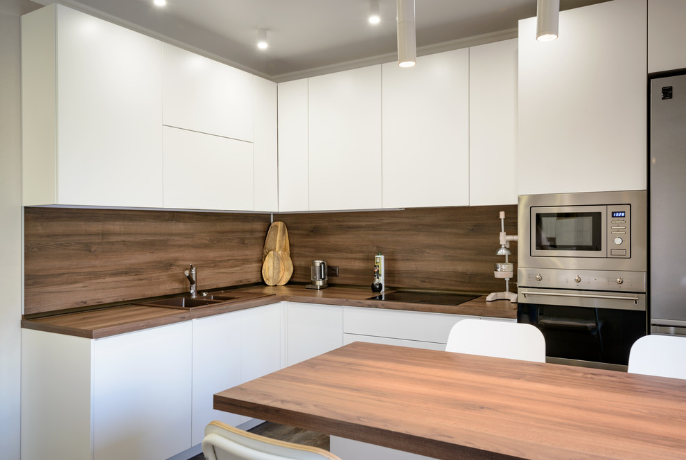Inspiration for a large contemporary l-shaped open plan kitchen in Novosibirsk with a drop-in sink, flat-panel cabinets, white cabinets, wood benchtops, brown splashback, timber splashback, stainless steel appliances, vinyl floors, with island, brown floor and brown benchtop.