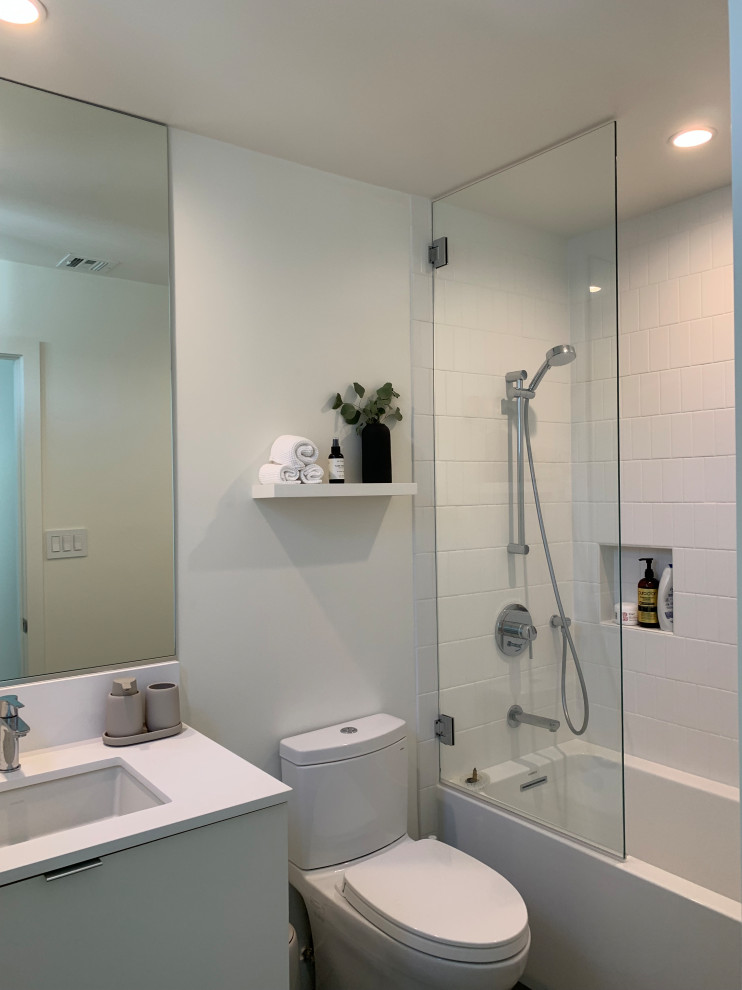 Exemple d'une petite salle d'eau moderne avec un placard à porte plane, des portes de placard blanches, une baignoire en alcôve, un combiné douche/baignoire, WC séparés, un carrelage blanc, des carreaux de céramique, un mur blanc, un sol en carrelage de porcelaine, un lavabo encastré, un plan de toilette en quartz modifié, un sol gris, une cabine de douche à porte battante, un plan de toilette blanc, meuble simple vasque et meuble-lavabo suspendu.