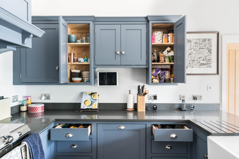 Large traditional u-shaped eat-in kitchen in Cambridgeshire with a farmhouse sink, beaded inset cabinets, blue cabinets, quartzite benchtops, medium hardwood floors, a peninsula and grey benchtop.