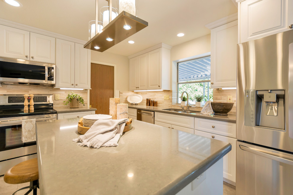 Inspiration for a large transitional l-shaped porcelain tile open concept kitchen remodel in Phoenix with an undermount sink, raised-panel cabinets, white cabinets, quartz countertops, beige backsplash, porcelain backsplash, stainless steel appliances and an island