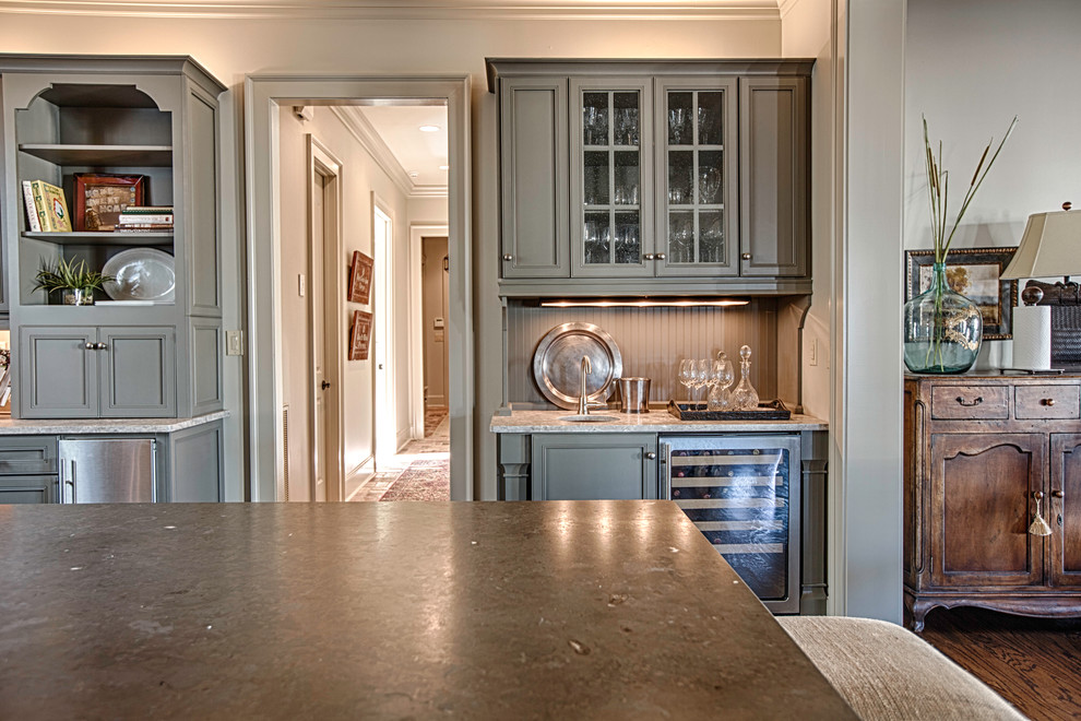 Large mountain style u-shaped medium tone wood floor open concept kitchen photo in Birmingham with a farmhouse sink, flat-panel cabinets, gray cabinets, limestone countertops, beige backsplash, stone tile backsplash, stainless steel appliances and an island