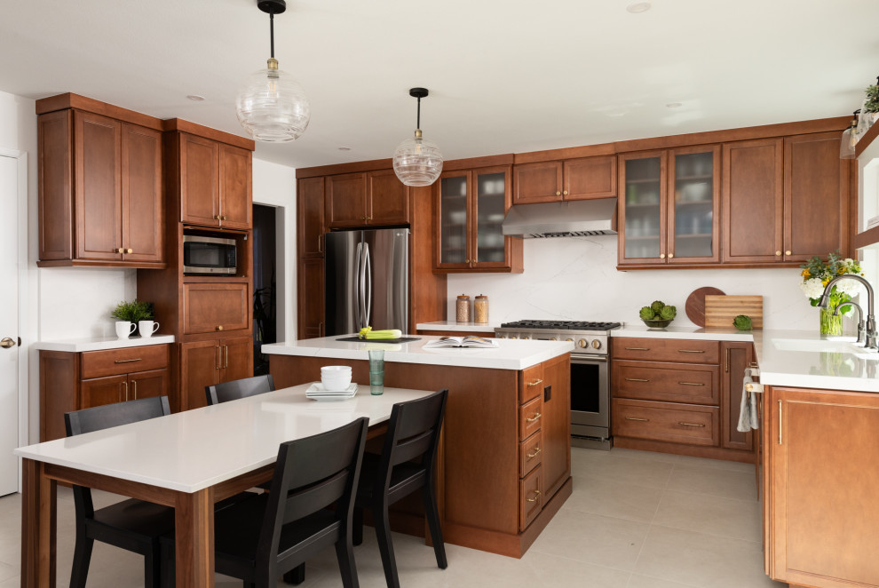 Example of a transitional porcelain tile and beige floor kitchen design in Orange County with an undermount sink, shaker cabinets, medium tone wood cabinets, quartz countertops, white backsplash, quartz backsplash, stainless steel appliances, an island and white countertops