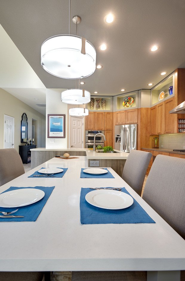 Photo of a mid-sized contemporary l-shaped eat-in kitchen in Sacramento with an undermount sink, shaker cabinets, light wood cabinets, solid surface benchtops, beige splashback, porcelain splashback, stainless steel appliances, travertine floors and with island.