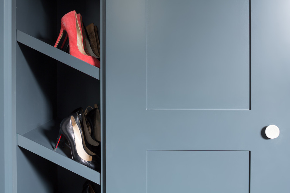 Transitional walk-in wardrobe in London with shaker cabinets and blue cabinets.