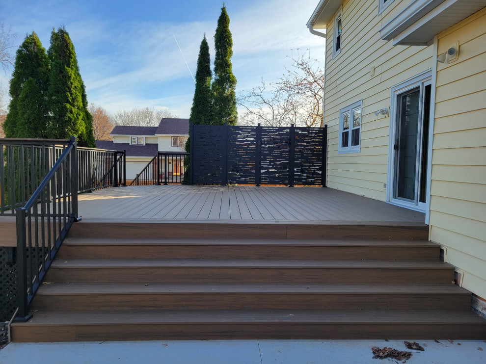 Example of a mid-sized backyard ground level privacy and metal railing deck design with no cover