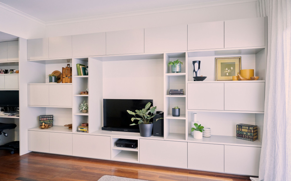 Cette photo montre une salle de séjour tendance de taille moyenne avec un mur blanc, un sol en bois brun, un téléviseur indépendant et un sol marron.
