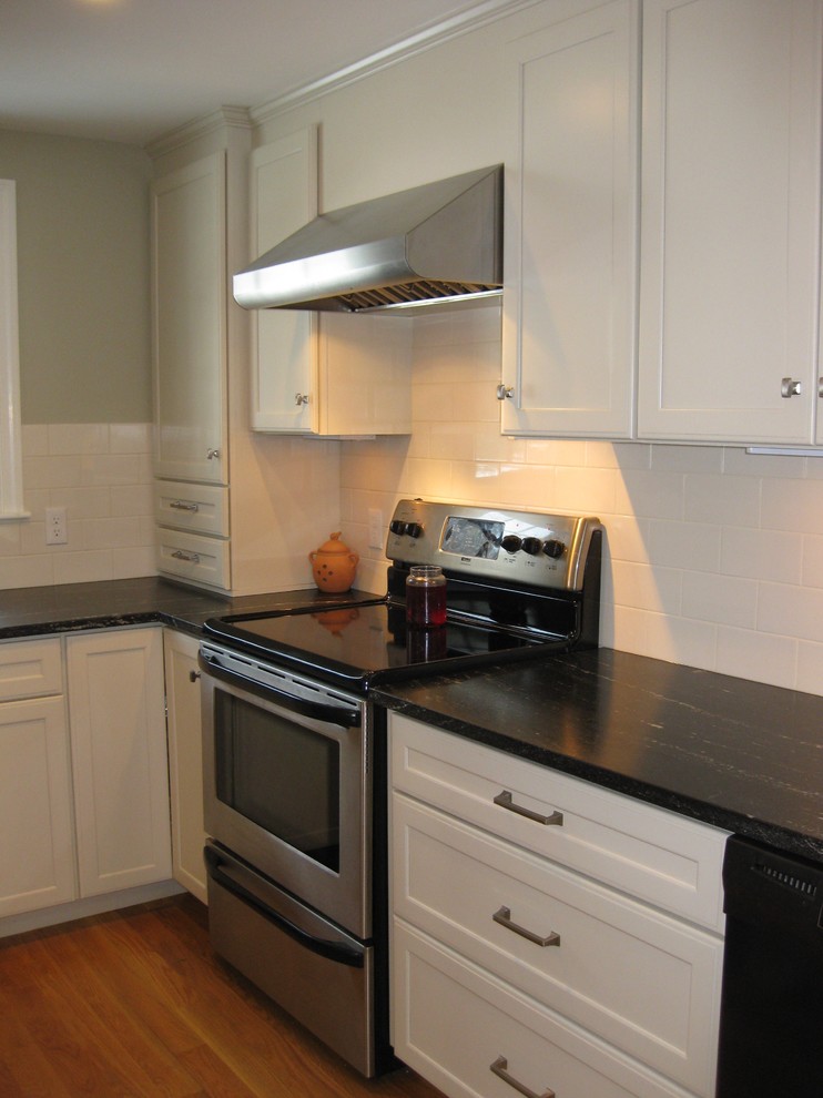 Eat-in kitchen - transitional l-shaped medium tone wood floor eat-in kitchen idea in Boston with an undermount sink, shaker cabinets, white cabinets, quartz countertops, white backsplash, ceramic backsplash, stainless steel appliances, an island and black countertops
