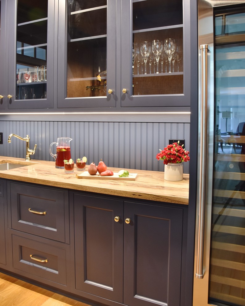 Photo of a home bar in Boston with an undermount sink, recessed-panel cabinets, blue cabinets, wood benchtops, blue splashback and timber splashback.