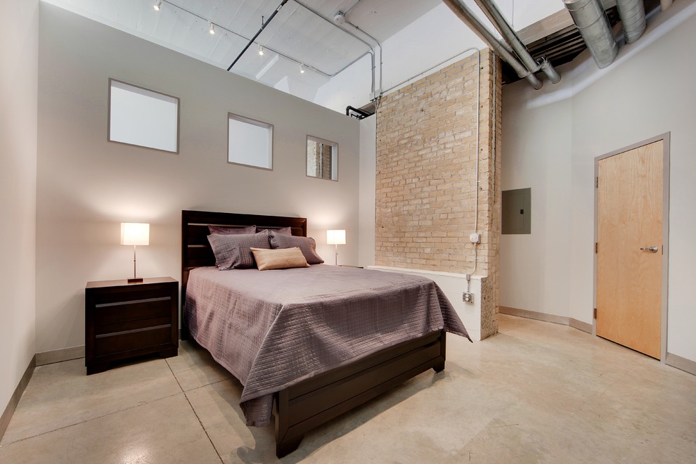 This is an example of a large industrial master bedroom in Minneapolis with grey walls, concrete floors, no fireplace and beige floor.