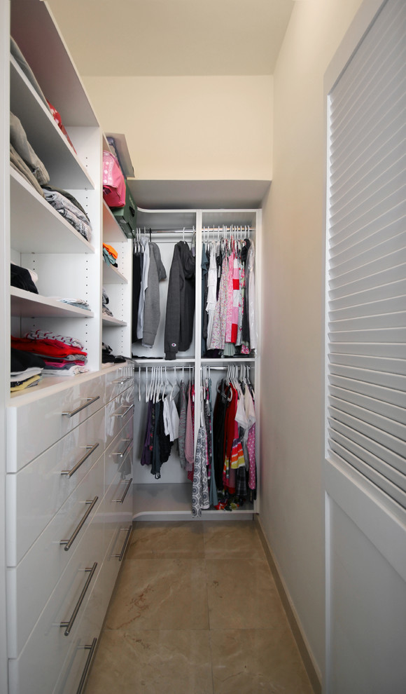 Inspiration for a small contemporary gender-neutral walk-in wardrobe in Miami with flat-panel cabinets, white cabinets, porcelain floors and beige floor.