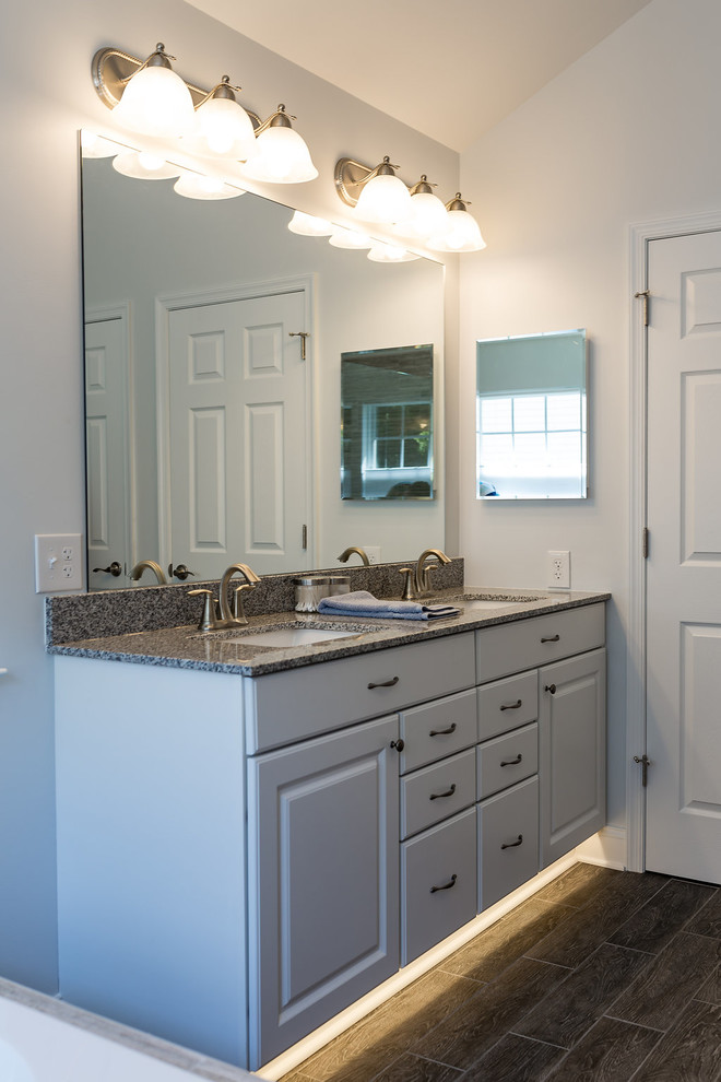 Large transitional master bathroom in Baltimore with white cabinets, a drop-in tub, an open shower, a one-piece toilet, gray tile, ceramic tile, an undermount sink, granite benchtops, porcelain floors, raised-panel cabinets and white walls.