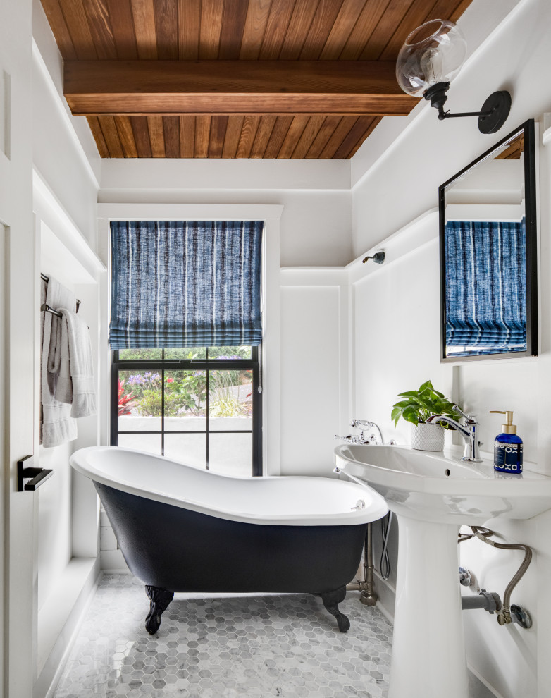 Photo of a beach style bathroom in Orange County with a claw-foot tub, white walls, a pedestal sink, grey floor, a single vanity, exposed beam, wood and decorative wall panelling.