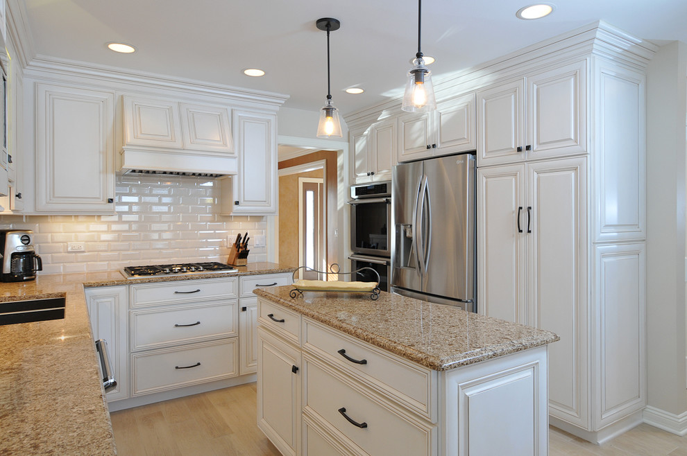 Mid-sized transitional l-shaped eat-in kitchen photo in Chicago with an undermount sink, raised-panel cabinets, white cabinets, quartz countertops, white backsplash, subway tile backsplash and stainless steel appliances