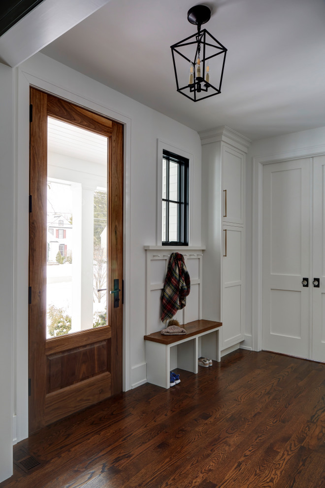 Landhaus Foyer mit weißer Wandfarbe, braunem Holzboden, Einzeltür, hellbrauner Holzhaustür und braunem Boden in Chicago