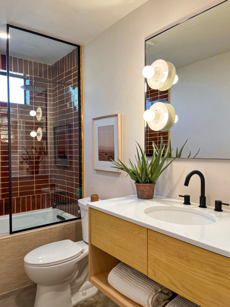 Inspiration for a bathroom in Los Angeles with flat-panel cabinets, medium wood cabinets, a built-in bath, a shower/bath combination, brown tiles, stone tiles, beige walls, concrete flooring, a submerged sink, engineered stone worktops, grey floors, an open shower, white worktops, a wall niche, a single sink and a floating vanity unit.