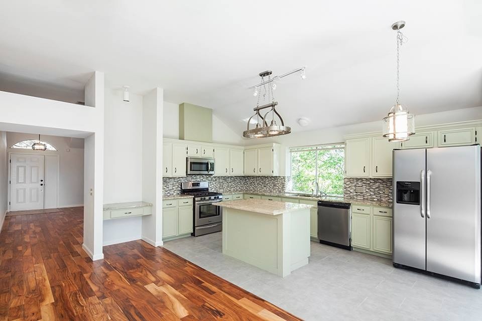 Inspiration for a mid-sized transitional l-shaped medium tone wood floor open concept kitchen remodel in Austin with an undermount sink, beaded inset cabinets, beige cabinets, granite countertops, multicolored backsplash, mosaic tile backsplash, stainless steel appliances and an island