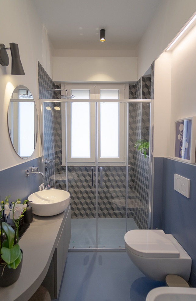 Photo of a medium sized contemporary bathroom in Other with flat-panel cabinets, grey cabinets, a wall mounted toilet, blue tiles, porcelain tiles, blue walls, porcelain flooring, a vessel sink, grey floors and a floating vanity unit.