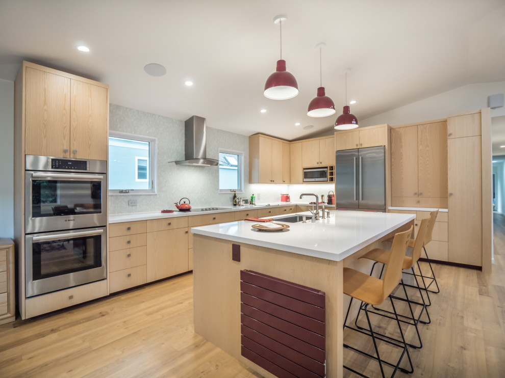 Contemporary l-shaped kitchen in Other with an undermount sink, flat-panel cabinets, light wood cabinets, grey splashback, stainless steel appliances, light hardwood floors, with island, beige floor, white benchtop and vaulted.