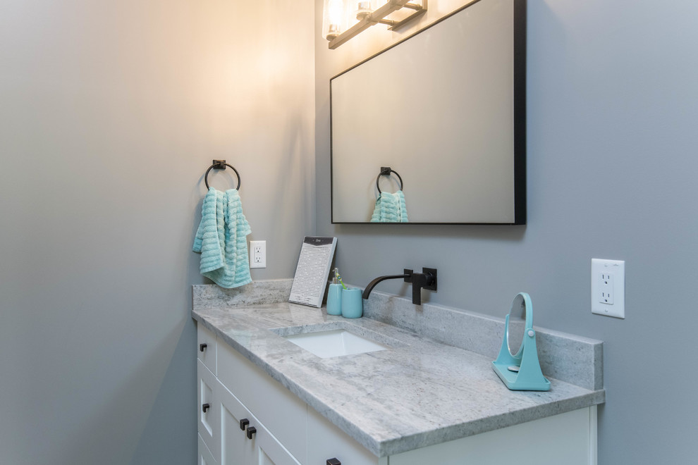 Organic Modern Mountain Home - A coastal beach-style bathroom featuring light blue accents, natural stone tiles, and a custom vanity, with white and gray tones creating a bright and airy atmosphere. This serene and sustainable design perfectly blends coastal charm and modern luxury in the organic mountain home