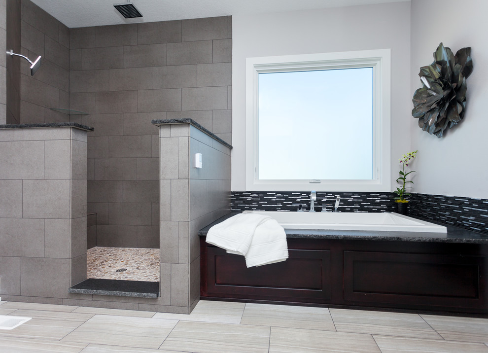 Design ideas for a mid-sized modern master bathroom in Other with a drop-in tub, a corner shower, recessed-panel cabinets, dark wood cabinets, gray tile, porcelain tile, grey walls, porcelain floors, granite benchtops, grey floor and an open shower.