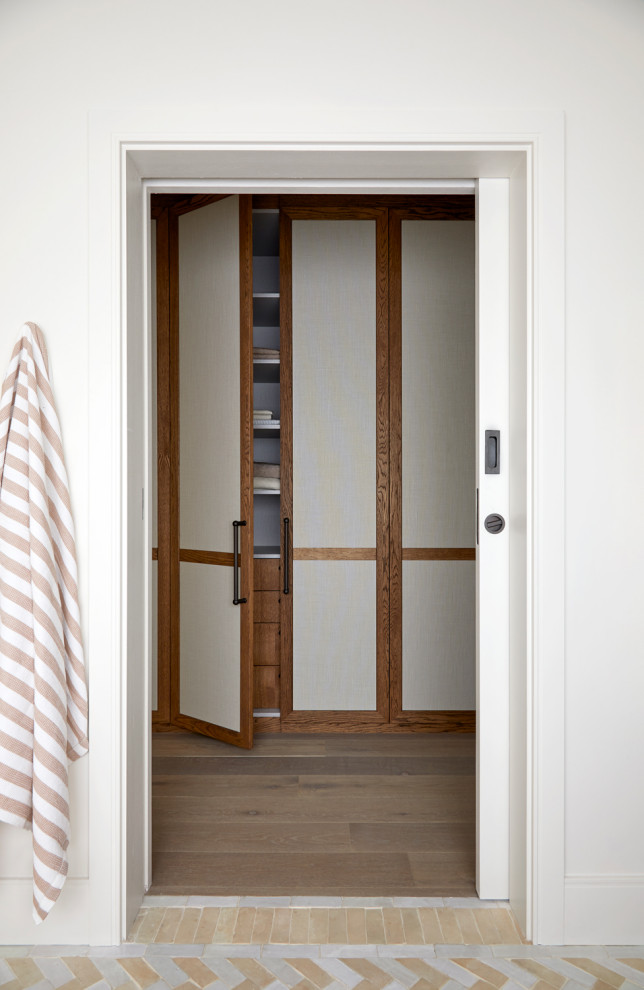 Réalisation d'une armoire encastrée nordique en bois brun de taille moyenne et neutre avec un placard avec porte à panneau encastré, tomettes au sol et un sol gris.