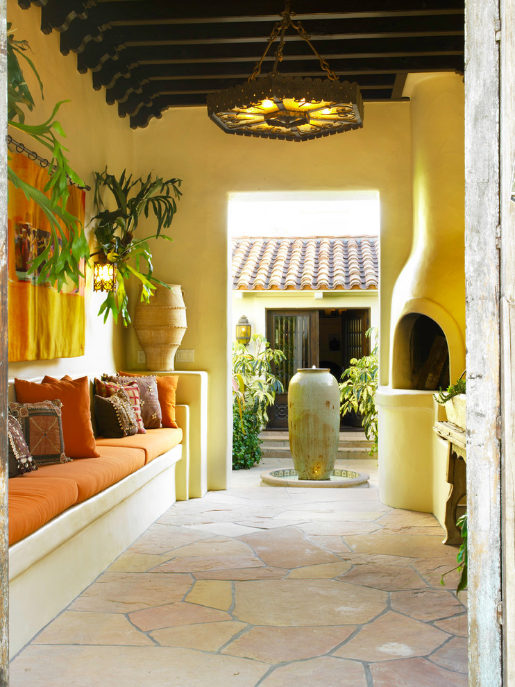 Photo of a mediterranean courtyard patio in Los Angeles with a roof extension, a fire feature and natural stone pavers.