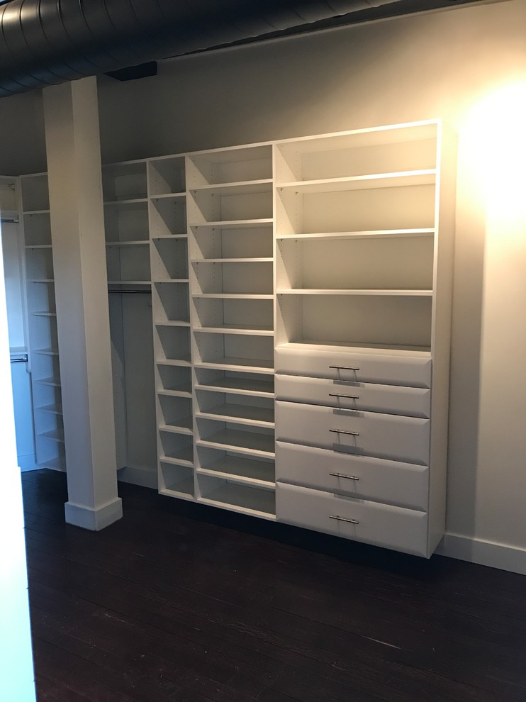 This is an example of a large traditional walk-in wardrobe in Detroit with white cabinets, dark hardwood floors and brown floor.